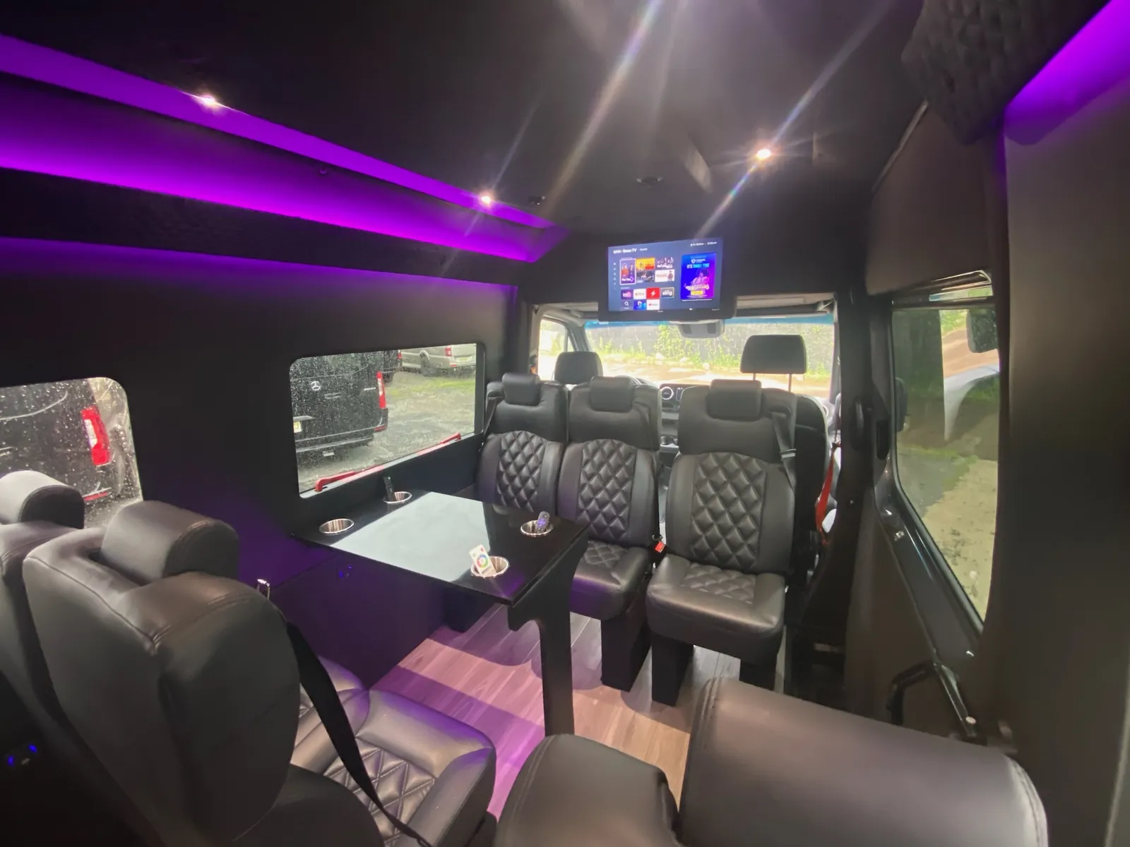 Executive Sprinter seating and a table beneath purple lighting — Sprinter van services in NYC